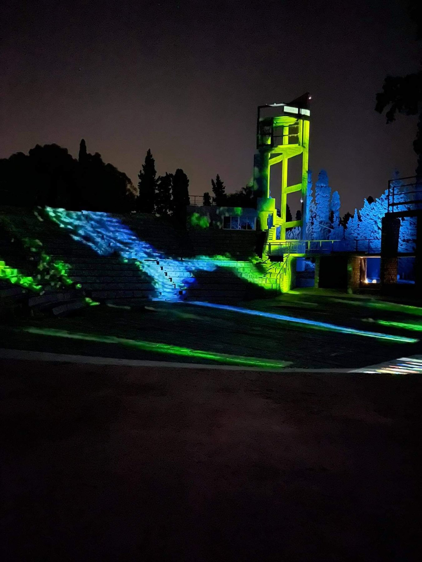 Green and blue projection across the stone tiers of the open-air theatre at Dar Sébastien, Hammamet, at night