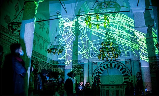The hall during the performance, generative lines across columns, arches and chandeliers, audience standing