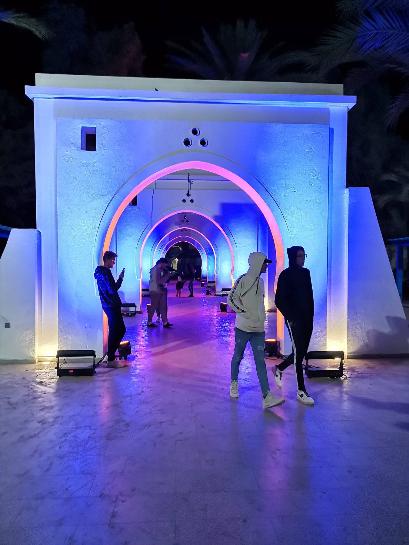 Visitors walking through the lit arches of the Arcades at night
