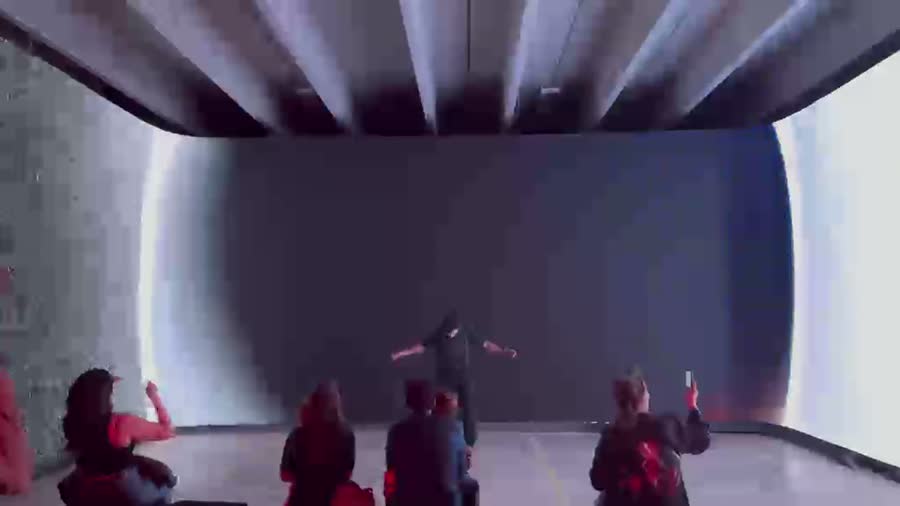 Visitor arms outstretched before a curved projection
